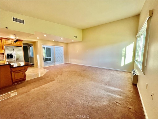 unfurnished living room with light carpet and a wall unit AC