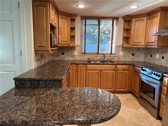 kitchen featuring sink, appliances with stainless steel finishes, dark stone countertops, decorative backsplash, and wall chimney exhaust hood