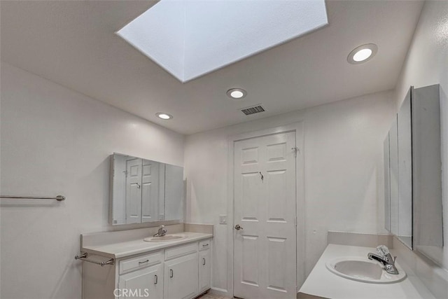 full bathroom with two vanities, recessed lighting, and a skylight