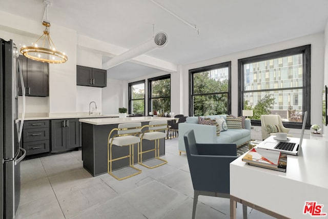 kitchen featuring stainless steel fridge, a breakfast bar, a kitchen island, decorative light fixtures, and a chandelier