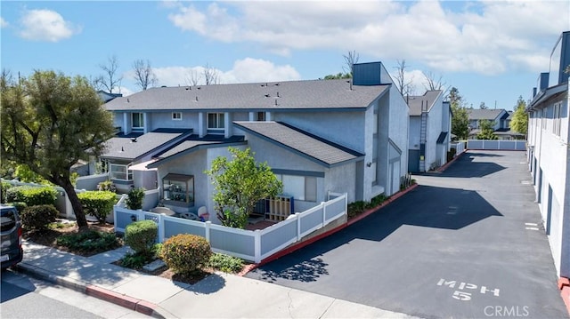 exterior space featuring a residential view, fence, and stucco siding