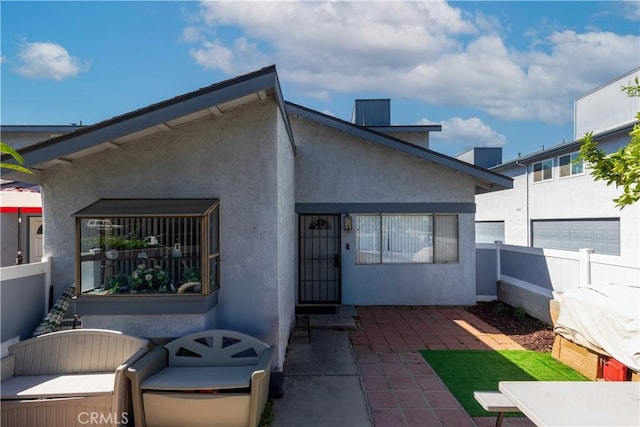 rear view of property with fence, a patio, and stucco siding