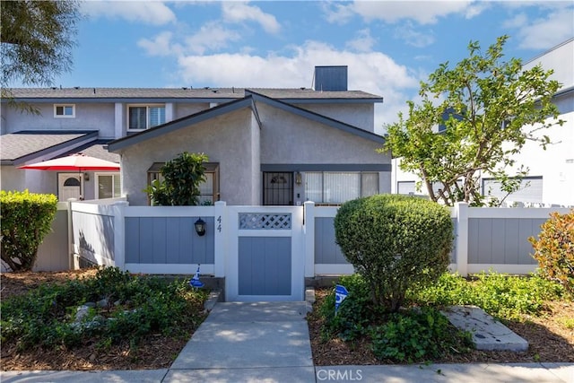 view of front facade with a fenced front yard, a gate, and stucco siding