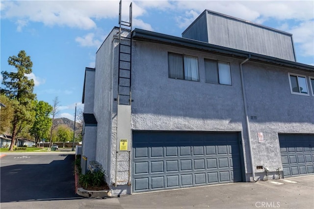 view of side of home with an attached garage and stucco siding