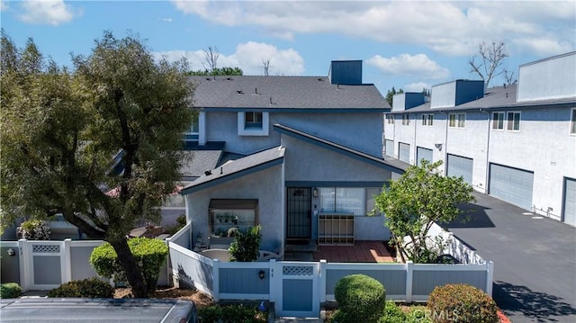 back of property featuring driveway, a fenced front yard, a gate, and stucco siding