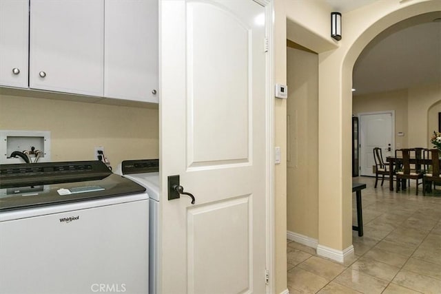 clothes washing area with cabinets, light tile patterned floors, and washer and clothes dryer