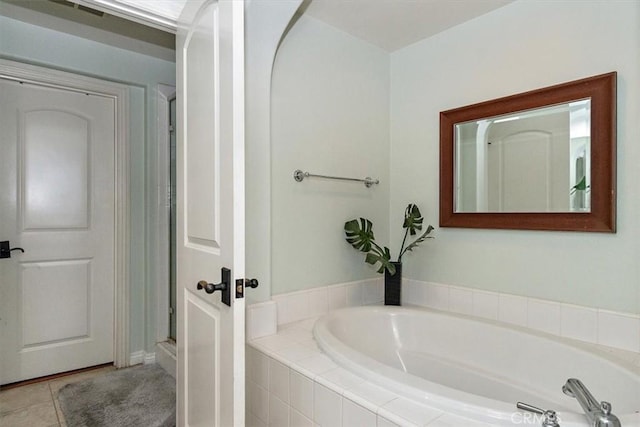 bathroom with tile patterned flooring and tiled tub