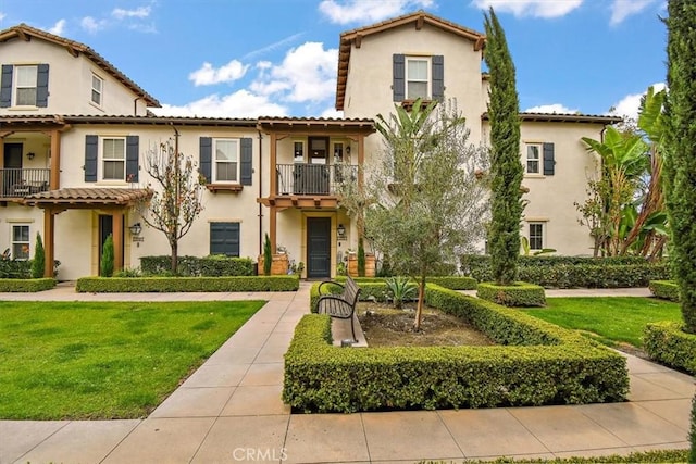 mediterranean / spanish house with a balcony and a front lawn