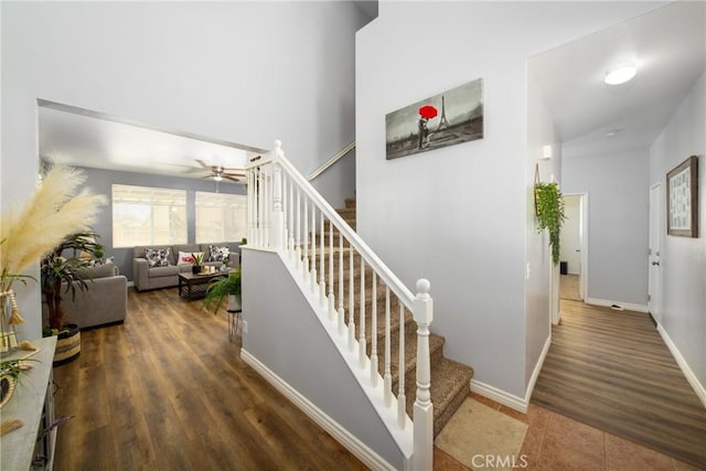 stairway with ceiling fan, wood finished floors, and baseboards