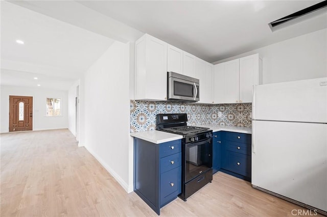 kitchen featuring white refrigerator, blue cabinets, black gas range, and white cabinets