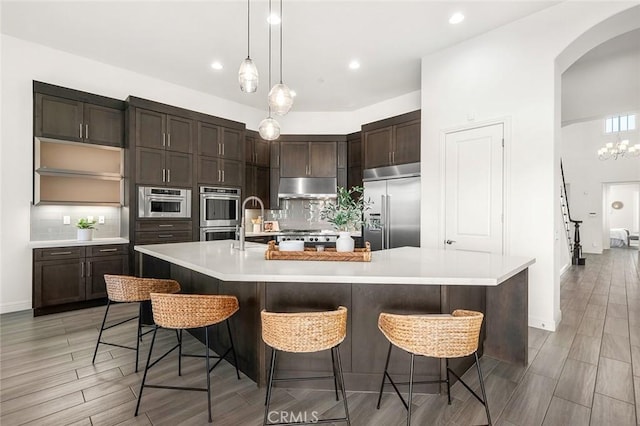 kitchen featuring dark brown cabinetry, appliances with stainless steel finishes, a kitchen breakfast bar, and a large island with sink