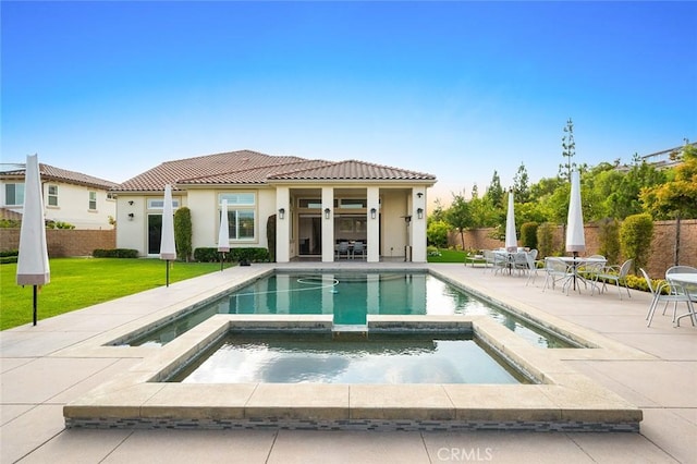 back of house featuring a swimming pool with hot tub, a yard, and a patio