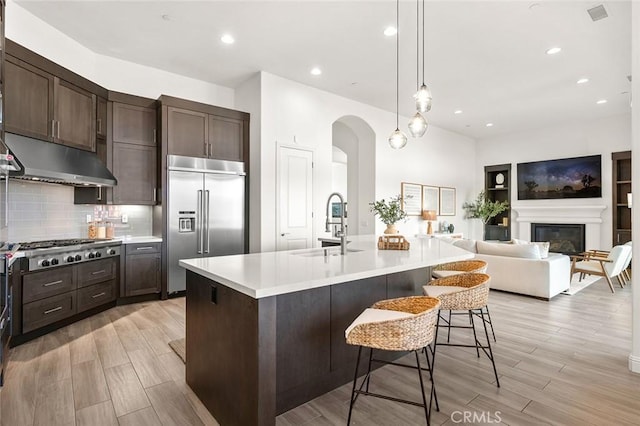 kitchen featuring a kitchen bar, sink, a center island with sink, appliances with stainless steel finishes, and pendant lighting