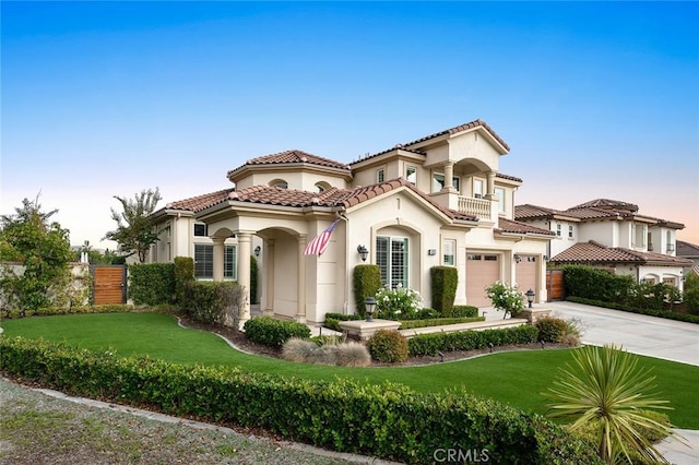 mediterranean / spanish house featuring a garage, a balcony, and a front yard