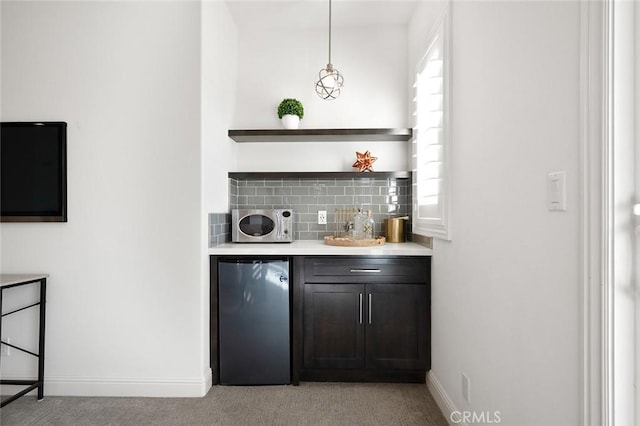 bar with hanging light fixtures, decorative backsplash, light colored carpet, and refrigerator