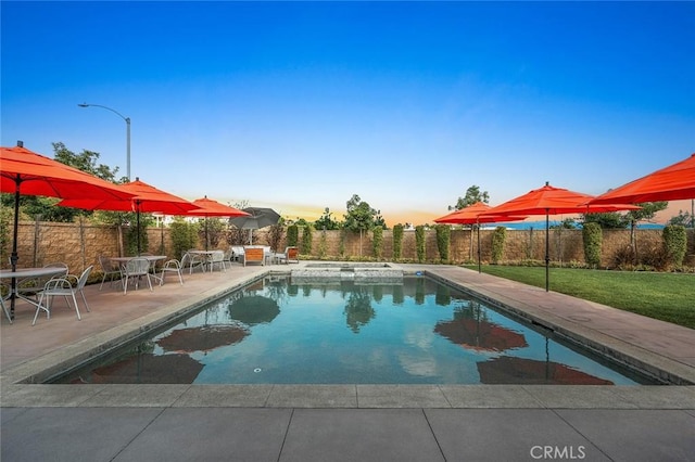 pool at dusk featuring a patio