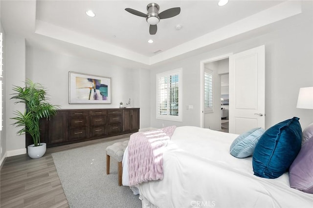 bedroom featuring ceiling fan, a raised ceiling, and light hardwood / wood-style flooring