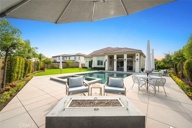 view of patio with a swimming pool with hot tub, an outdoor structure, and a fire pit