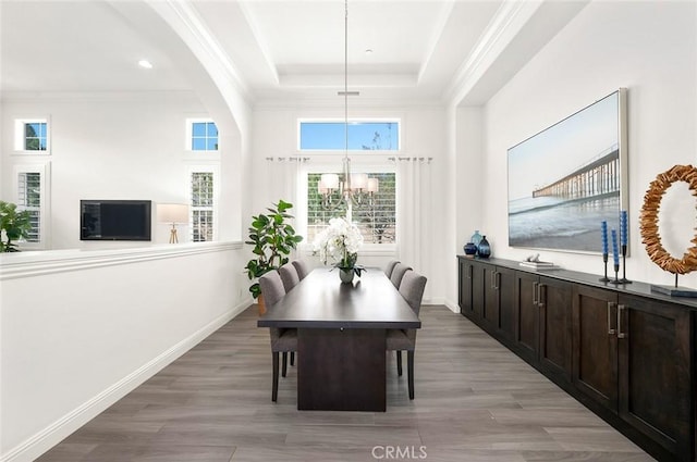 dining room featuring hardwood / wood-style floors, ornamental molding, a raised ceiling, and a chandelier