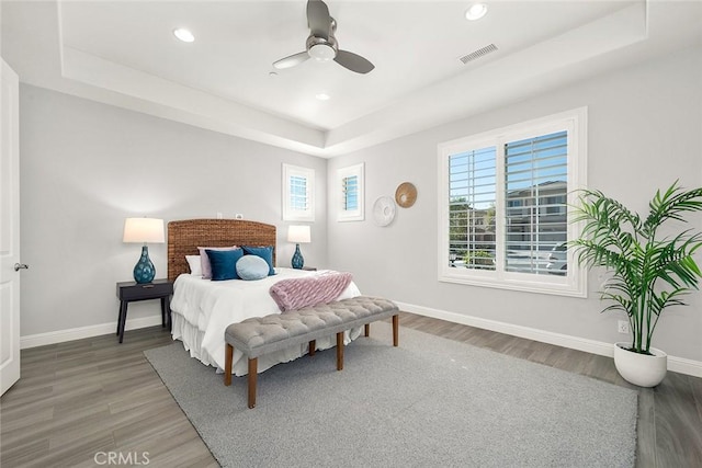 bedroom with a tray ceiling, wood-type flooring, and ceiling fan