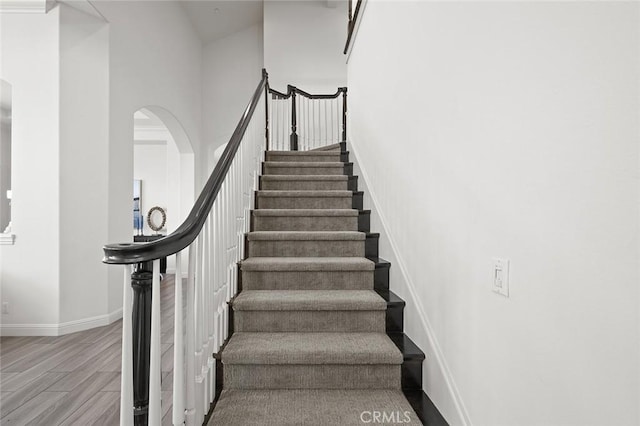 stairway with hardwood / wood-style flooring and a towering ceiling