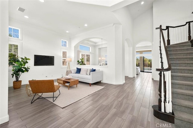 living room with a high ceiling, crown molding, and a healthy amount of sunlight