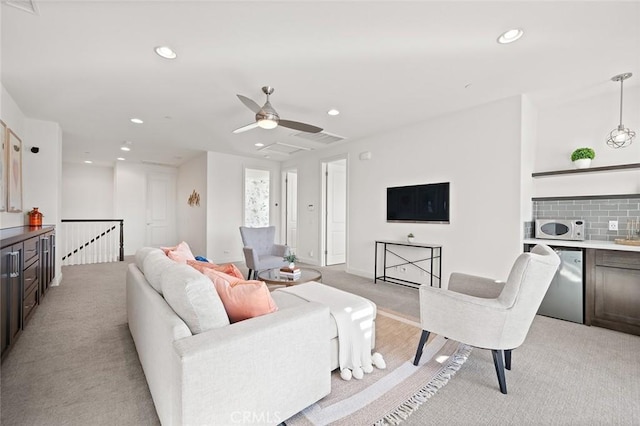 living room featuring ceiling fan, light colored carpet, and bar