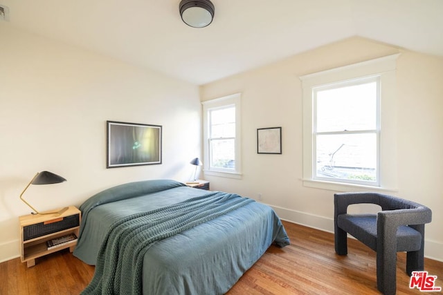 bedroom with multiple windows, vaulted ceiling, and light hardwood / wood-style flooring