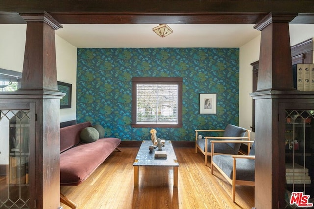 living room featuring wood-type flooring, a large fireplace, and ornate columns