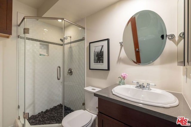 bathroom featuring vanity, an enclosed shower, and toilet