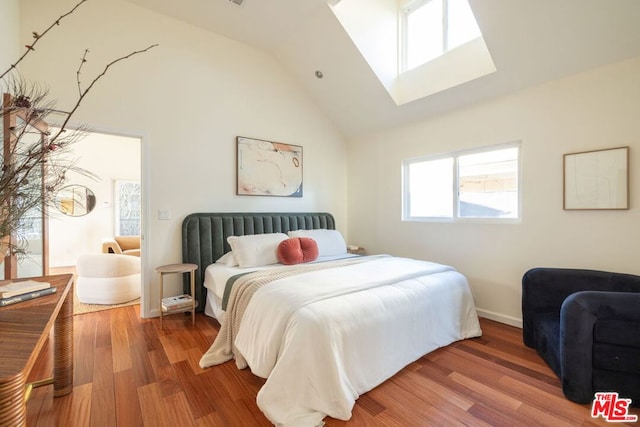 bedroom featuring vaulted ceiling with skylight and hardwood / wood-style floors