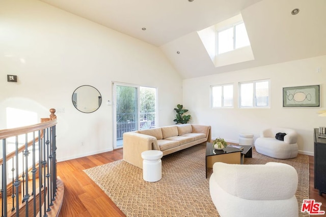 living room featuring vaulted ceiling with skylight and hardwood / wood-style floors