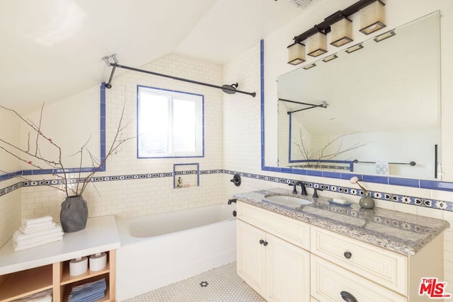 bathroom with tile patterned floors, vaulted ceiling, tile walls, vanity, and tiled shower / bath combo