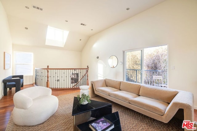 living room featuring hardwood / wood-style floors and vaulted ceiling with skylight