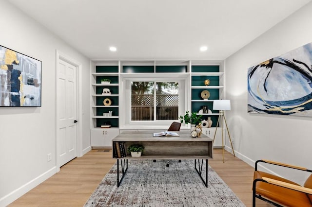 home office with light hardwood / wood-style floors and built in shelves