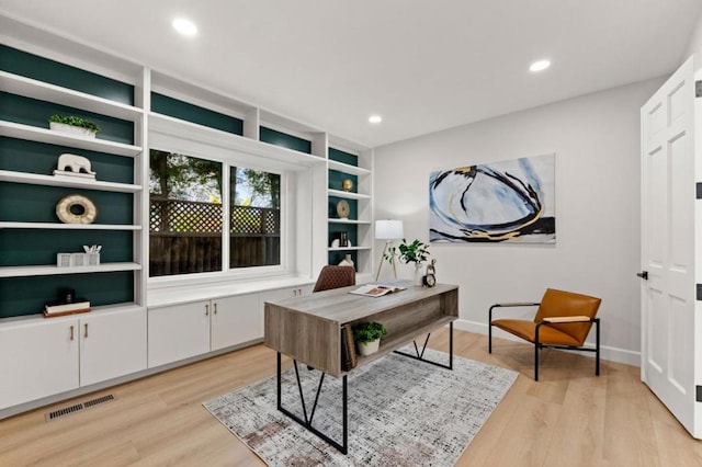 office area with built in features and light wood-type flooring