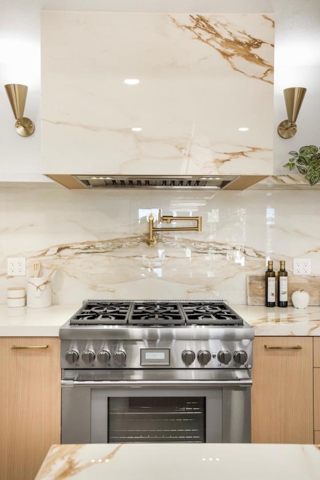 kitchen with light stone countertops, stainless steel stove, decorative backsplash, and light brown cabinets