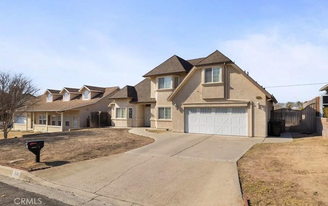 traditional home featuring stucco siding, a gate, fence, a garage, and driveway