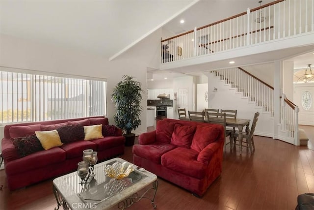 living area with stairs, wood finished floors, and a towering ceiling