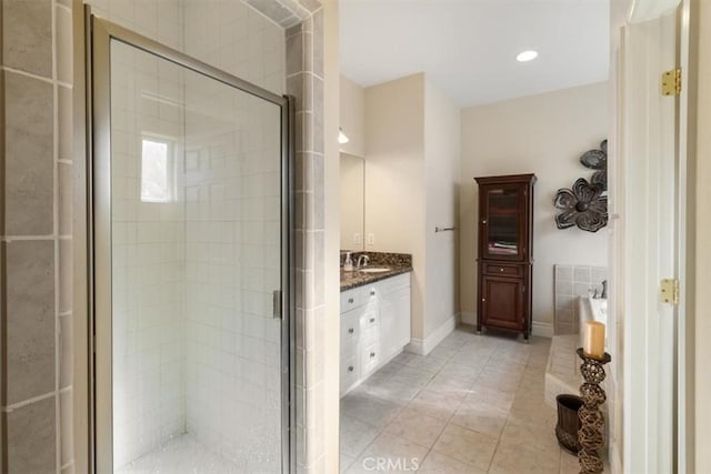 bathroom with a bathtub, a stall shower, vanity, and baseboards