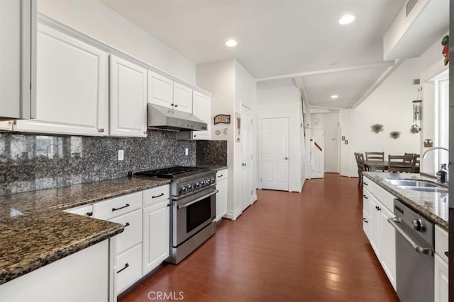 kitchen featuring stainless steel appliances, backsplash, white cabinets, a sink, and under cabinet range hood