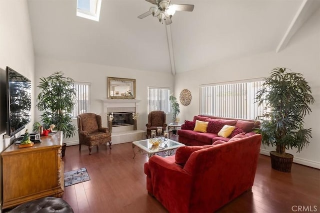 living room featuring a skylight, a ceiling fan, hardwood / wood-style flooring, a fireplace, and high vaulted ceiling