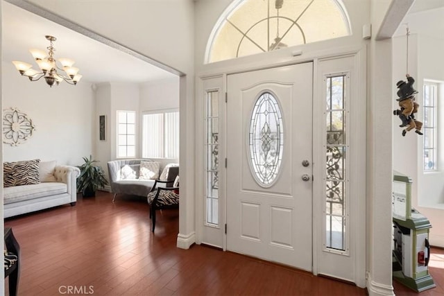 entrance foyer with dark wood-type flooring, plenty of natural light, and a notable chandelier