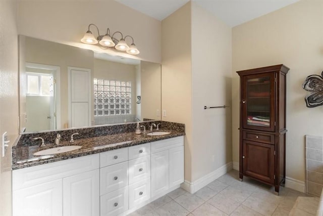 full bathroom featuring double vanity, tile patterned flooring, a sink, and baseboards