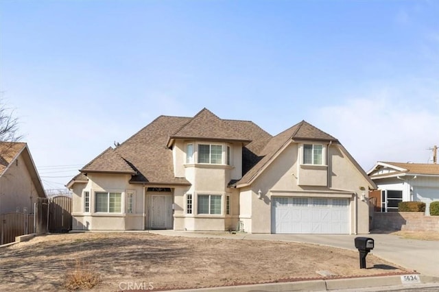 view of front facade with roof with shingles, a gate, concrete driveway, and stucco siding