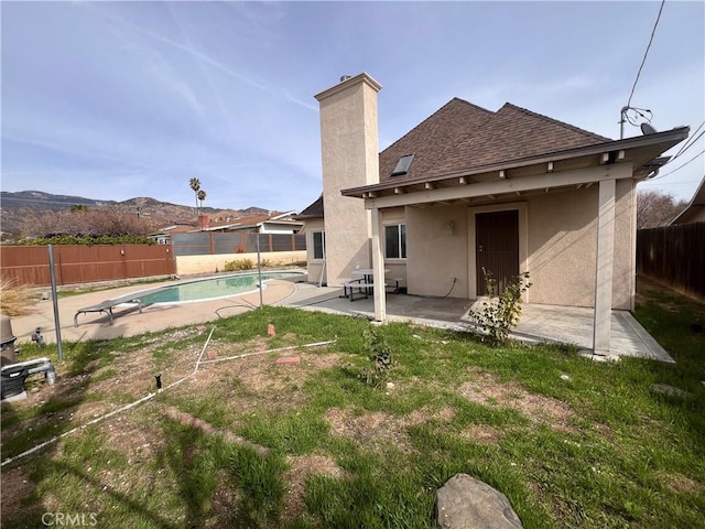 back of house with a fenced backyard, a shingled roof, a fenced in pool, stucco siding, and a patio area