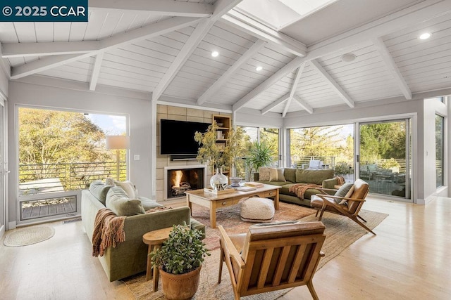 sunroom / solarium with wood ceiling, a wealth of natural light, lofted ceiling with beams, and a tile fireplace