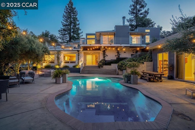 pool at dusk with an outdoor hangout area and a patio