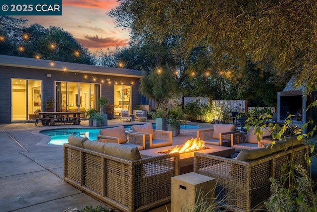 patio terrace at dusk with an outdoor living space with a fire pit