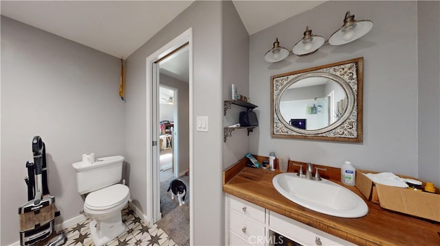 bathroom featuring toilet, vanity, and baseboards